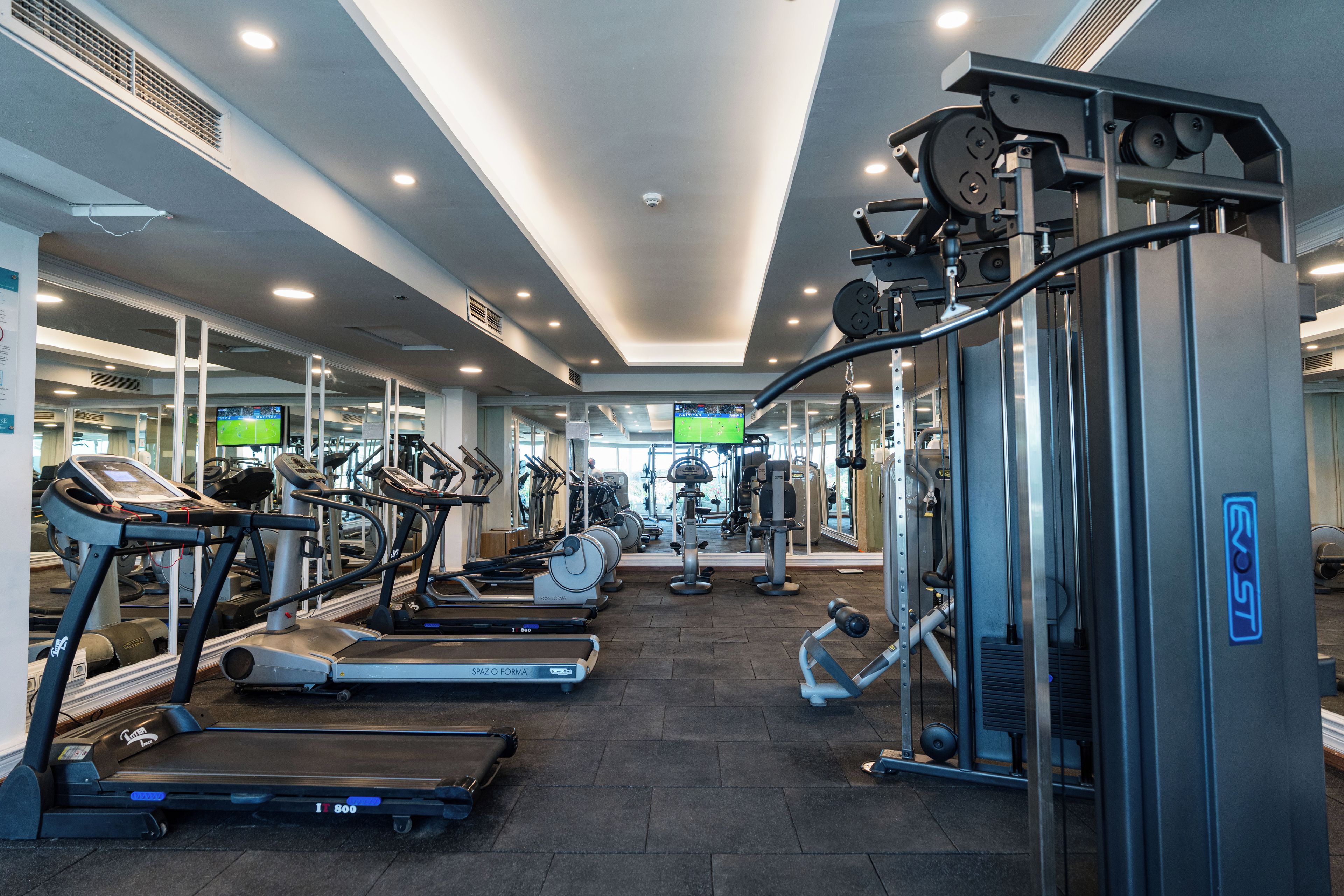 Un gimnasio con cintas de correr, elípticas y equipos de levantamiento de pesas.