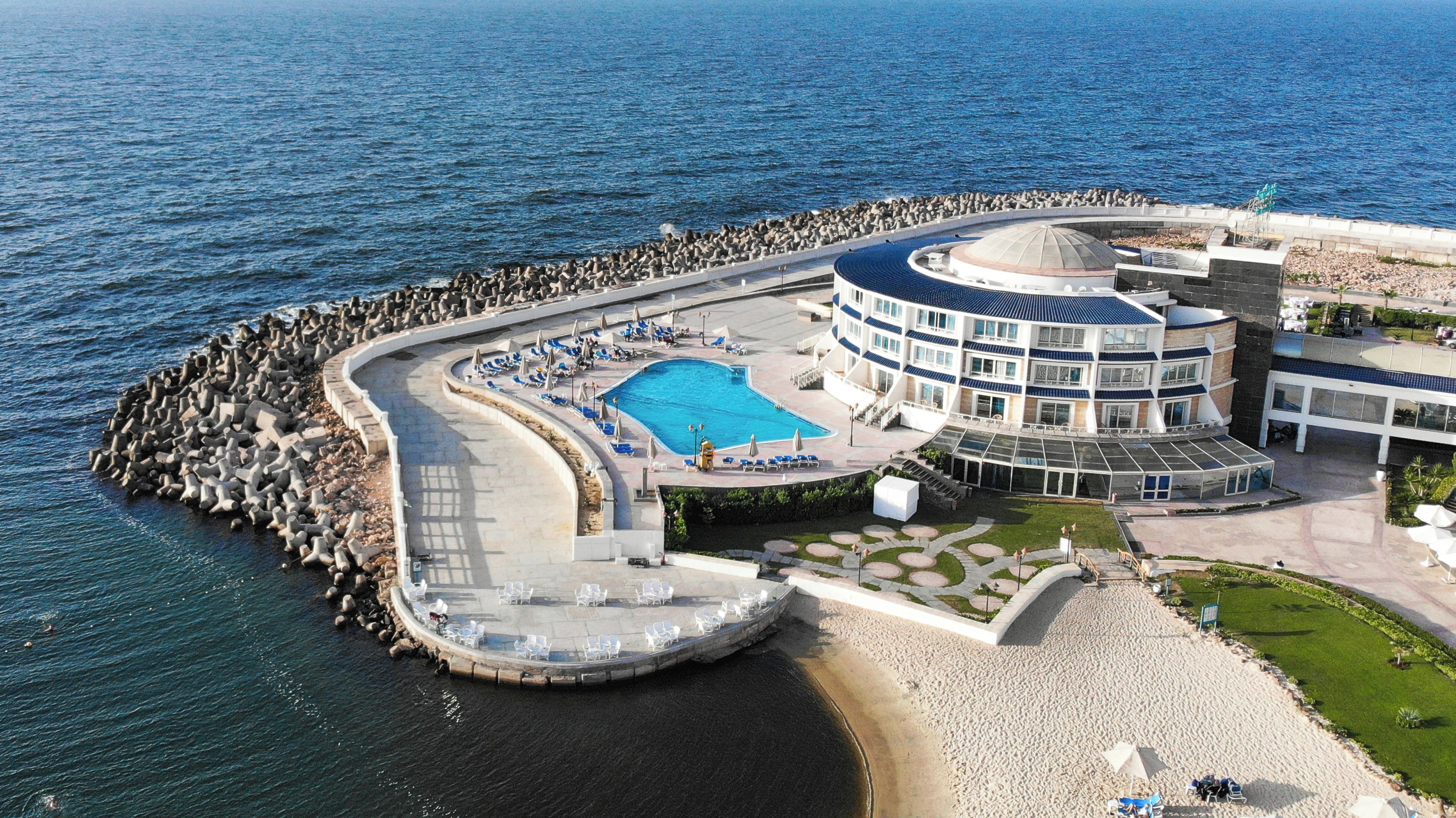 A resort with a large pool, a beach area, and a building with a dome structure.