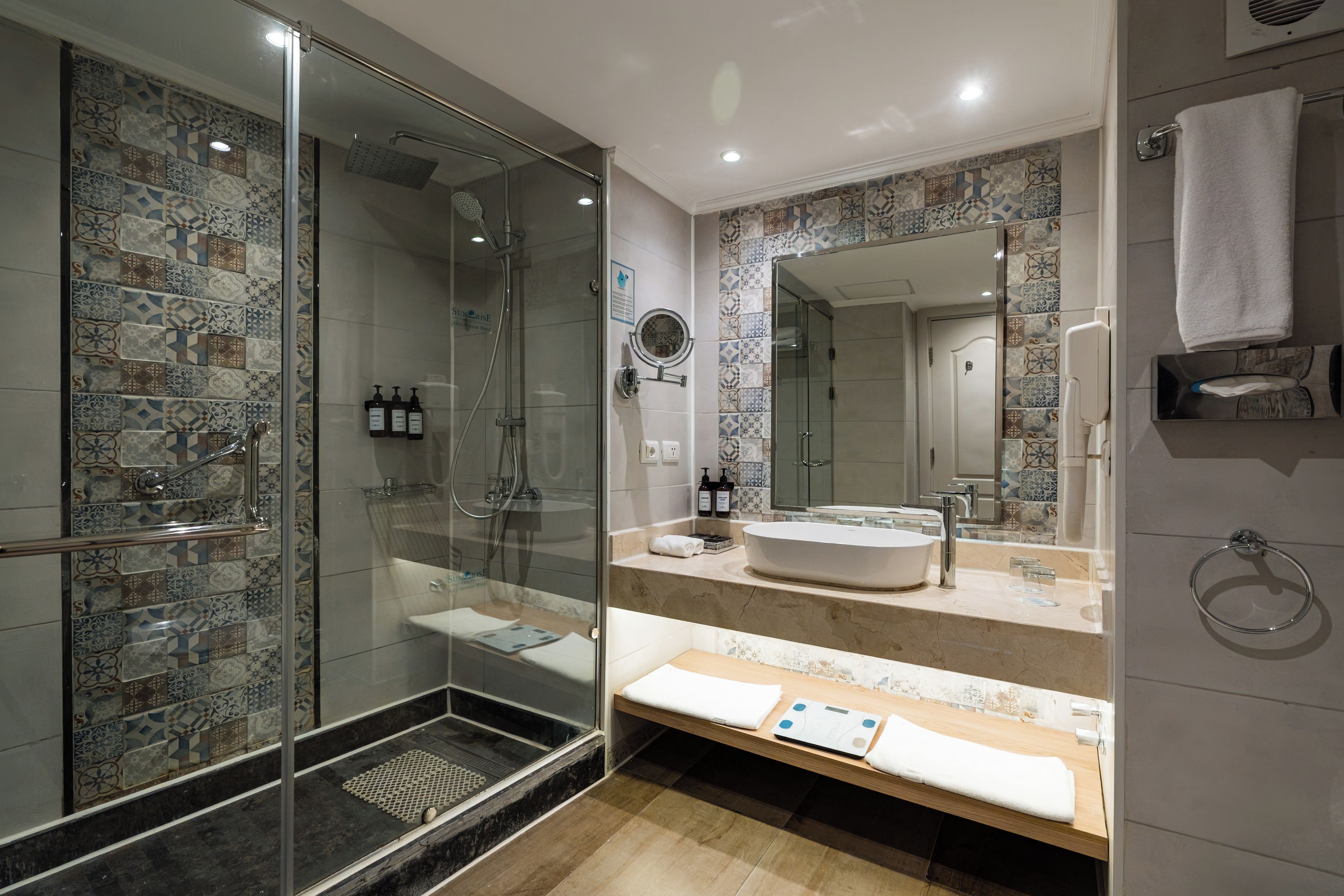 A modern bathroom with a glass-enclosed shower, a large mirror, and a vanity with a sink and towel rack.
