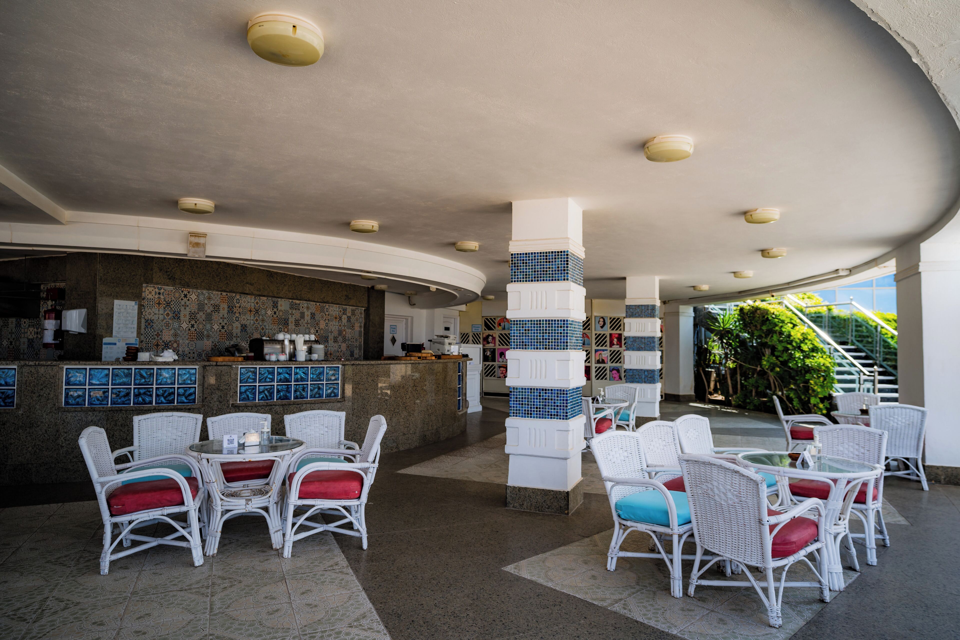 Un área de recepción con techo curvo, mobiliario de mimbre blanco y pared con azulejos.