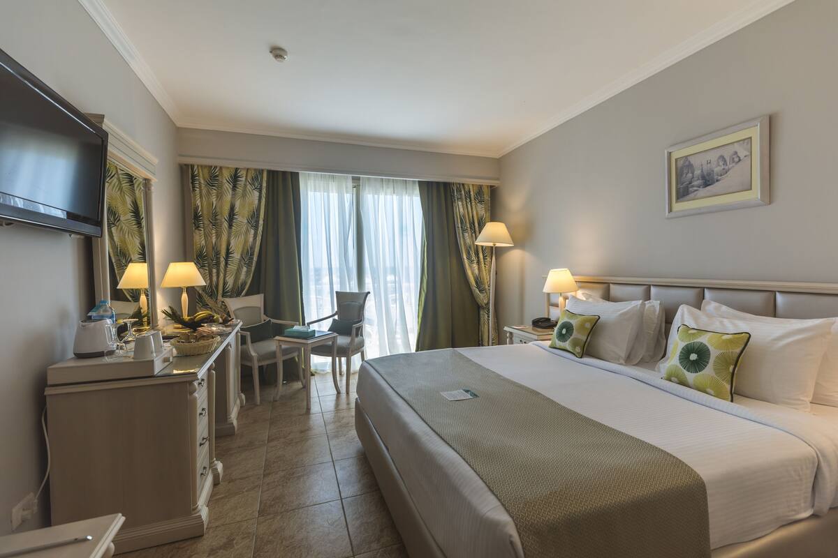 Une chambre d’hôtel équipée d’un lit, d’un bureau, d’une chaise et d’un téléviseur fixé au mur.