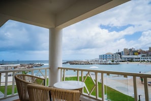 Enjoy the ocean view from this balcony with a wicker chair and small table.