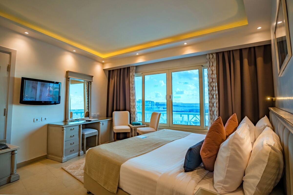 Une chambre d’hôtel équipée d’un lit, d’un bureau, d’une chaise et d’un téléviseur fixé au mur.
