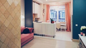 A modern kitchen with a central island, a dining area with a table and chairs, and a living space with a sofa and a coffee table. - MalinaApt Alice in Wonderland (Kyiv)