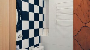 A bathroom with a checkered wall pattern, a white sink, a toilet, and a wooden door. - MalinaApt Alice in Wonderland (Kyiv)