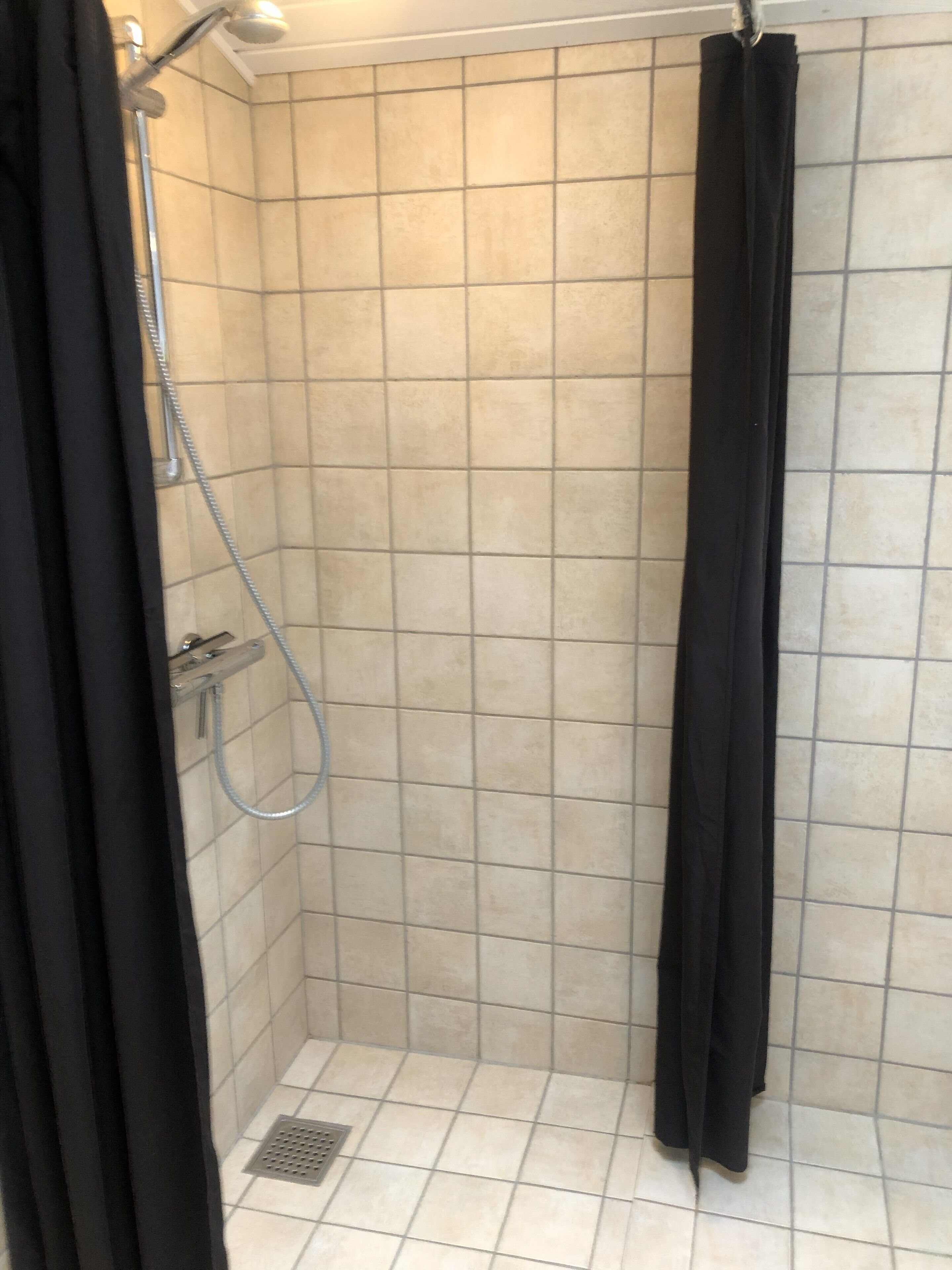 A small, tiled shower stall with a showerhead and a curtain.