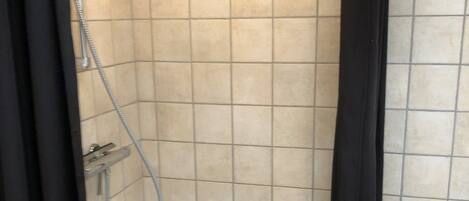 A small, tiled shower stall with a showerhead and a curtain.