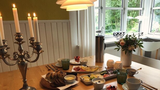 A dining table with various dishes, a candelabra, and a window with a view of greenery.