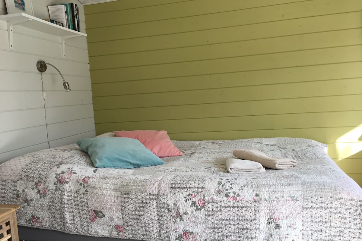 Una cama con un edredón floral, dos almohadas y dos toallas dobladas.