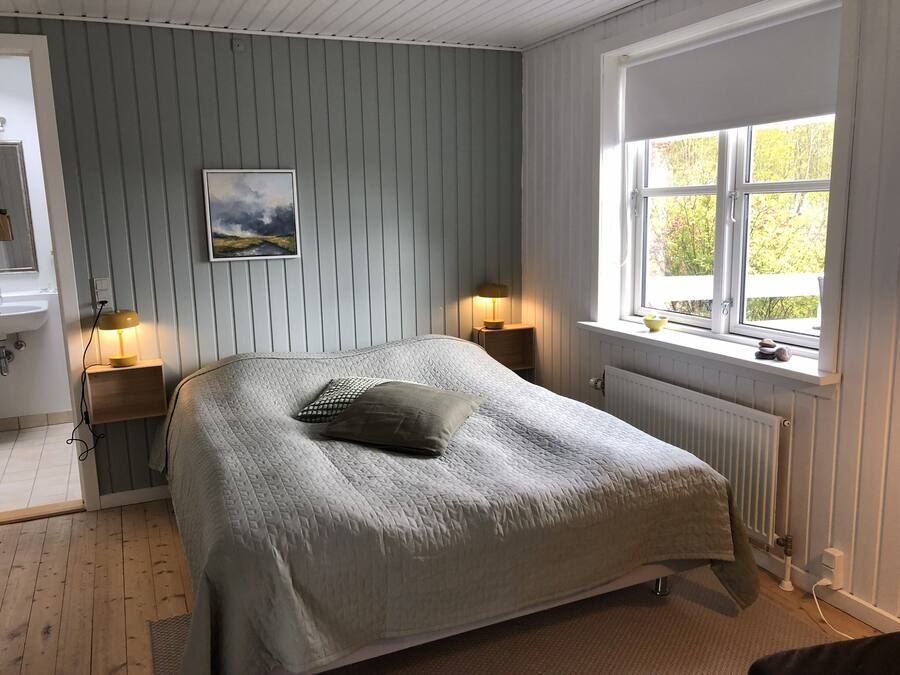 Ein Schlafzimmer mit Bett, Nachttischlampen, einem Fenster mit Blick und einem Bild an der Wand.