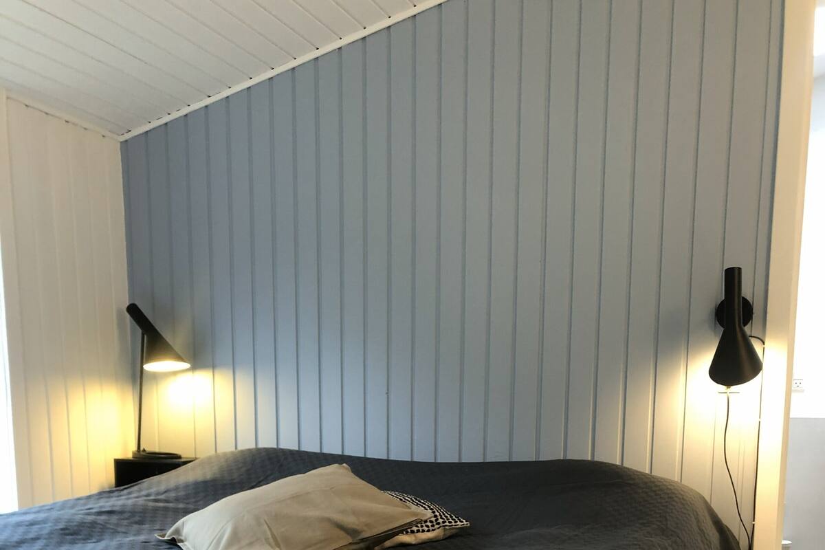 Un dormitorio con una cama, una lámpara de noche y un aplique de pared.