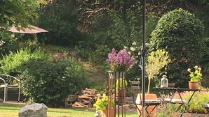 A garden with a metal table, chairs, and a stone structure.