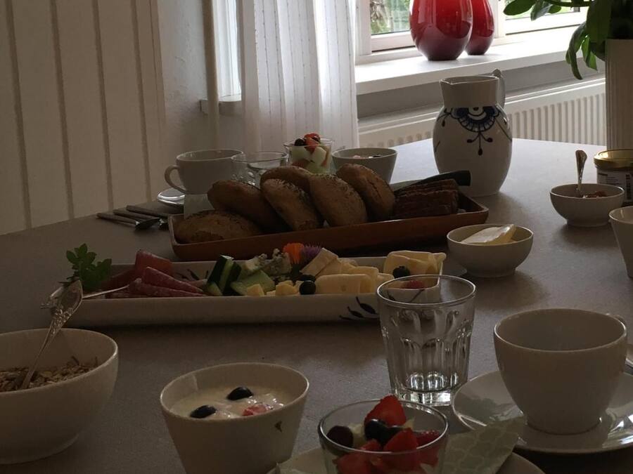 Una mesa de desayuno con diversos alimentos, como pan, frutas y un vaso de agua.