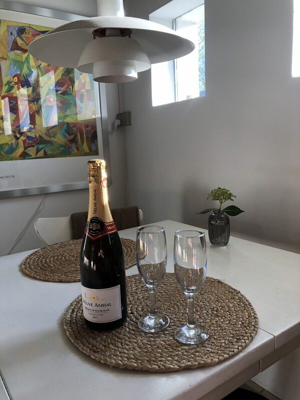 A bottle of Veuve Amiral wine, two empty wine glasses, and a small potted plant on a table with a woven placemat. - Heltoften Bed & Breakfast (Nykobing Mors)