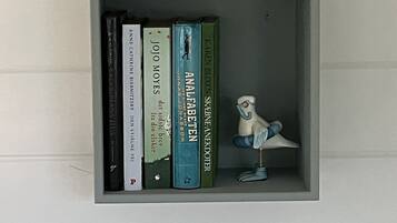 Una estantería con libros y una pequeña figurita de pájaro.