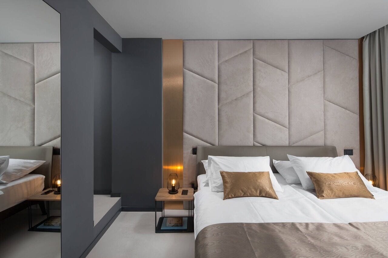 A modern hotel room with a large bed, a nightstand, and a sofa.