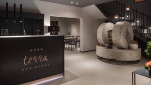 A modern reception area with a black counter, a staircase, and a dining area in the background. - Terra Residence (Labin)