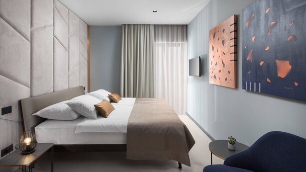 A modern hotel room with a large bed, a bedside table, a chair, and a TV. - Terra Residence (Labin)