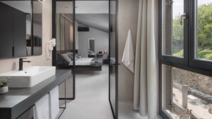 A modern hotel bathroom with a large mirror, a white sink, and a shower area. - Terra Residence (Labin)