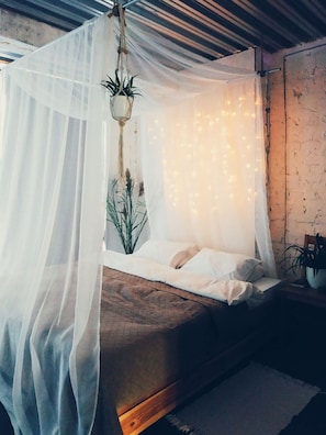 A bed with a canopy, a hanging plant, and fairy lights. - MalinaApt  Bohemian Loft (Kyiv)