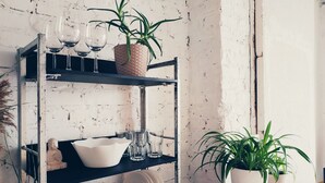 A rustic kitchen with a metal shelf holding wine glasses, a bowl, and a plant. - MalinaApt  Bohemian Loft (Kyiv)