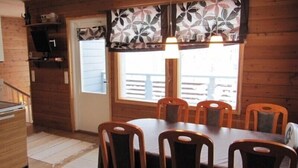 A wooden interior with a dining table, chairs, and a window with a view. - Rukako JYRKKÄLÄ A (Kuusamo)