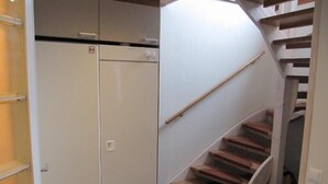A narrow hallway with a white refrigerator and a wooden staircase. - Rukako JYRKKÄLÄ A (Kuusamo)