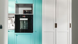 A kitchen with teal cabinets, a black oven, and a white door. - MalinaApt Mushka (Kyiv)