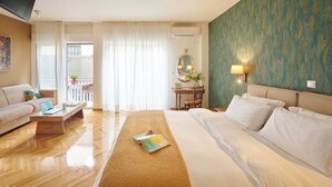 A hotel room with a bed, a sofa, a small table, a mirror, and a view of the balcony. - Rastoni Athens Suites near Acropolis (Athens)