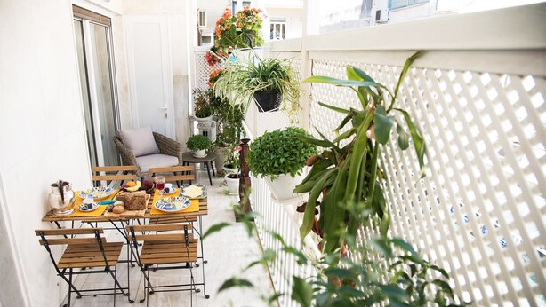 A narrow outdoor balcony with a table set for breakfast, surrounded by potted plants and a white lattice fence. - Rastoni Athens Suites near Acropolis (Athens)