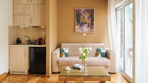 A compact living space with a kitchenette, a sofa, a coffee table, and a painting on the wall. - Rastoni Athens Suites near Acropolis (Athens)