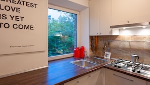 A modern kitchen with a large window, stainless steel appliances, and a minimalist design. - MalinaApt  Sophisticated red (Kyiv)