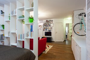 A modern living room with a red sofa, white shelving units, a television, and a bicycle mounted on the wall. - MalinaApt  Sophisticated red (Kyiv)