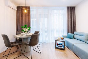 A modern living room with a dining area, a sofa, and a table set for four. - MalinaApt Odri Dynamique (Kyiv)