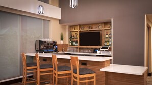 A modern bar area with wooden bar stools, a coffee machine, and a wine cooler.