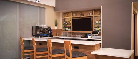 A modern bar area with wooden bar stools, a coffee machine, and a wine cooler.