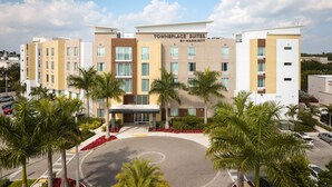 A multi-story hotel with a modern design, featuring a central entrance and a parking area.