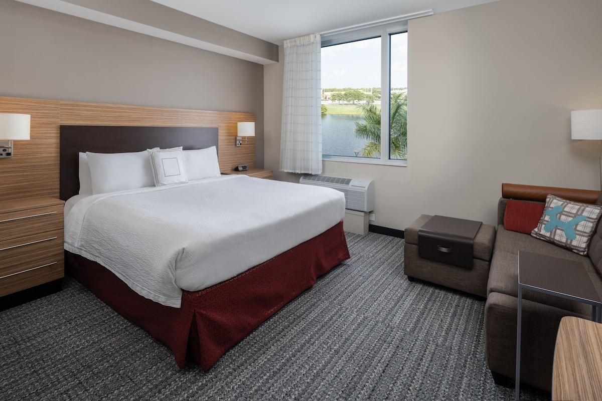Une chambre d’hôtel avec un grand lit, un bureau, une chaise, un canapé et une fenêtre donnant sur un plan d’eau.