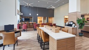 A modern hotel lobby with a central island, seating area, and a bar.