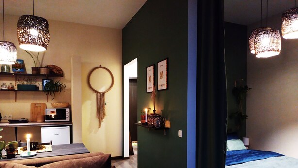 Een gezellige woonkamer met een bank, een eethoek met een magnetron, en een bed met een blauwe spreidekker.