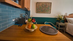Une cuisine avec un plan de travail en bois, une corbeille de fruits, une assiette décorée et un tableau accroché au mur.