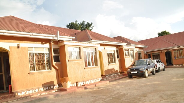 A row of single-story houses with a uniform architectural style, featuring large windows and a flat roof. - Square Suites (Mbarara)