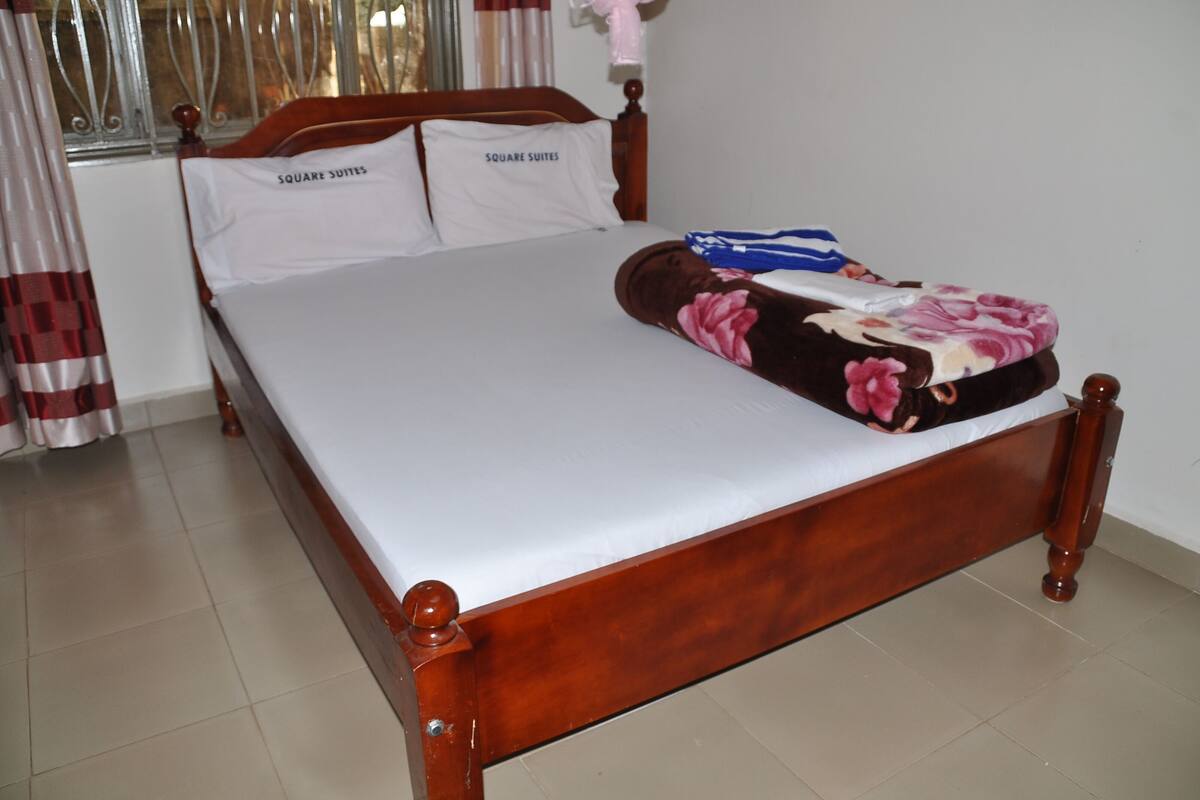 A bed with a wooden frame, white bedding, and a floral blanket.