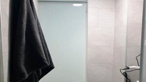 Een kleine badkamer met een toilet, een prullenbak en een handdoek aan de muur.