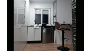 Een moderne keuken met witte kastjes, een roestvrijstalen koelkast en een houten barstoel.