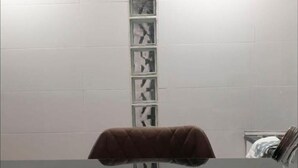 Een badkamer met een witte betegelde muur, een bruine handdoek aan een rek en een spiegel.