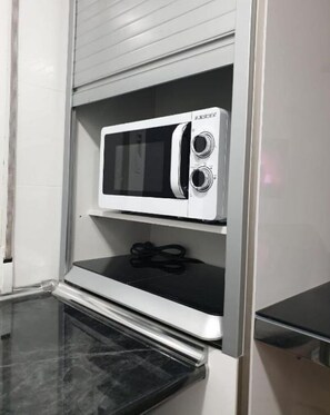 Compact kitchenette with microwave oven and countertop.