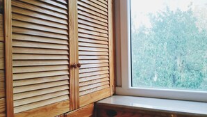 A wooden wardrobe with horizontal slats and a window with a view of trees. - MalinaApt Hello Geometry (Kyiv)