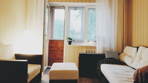 A cozy room with a bed, a chair, a small table with a plant, and a window with curtains. - MalinaApt Hello Geometry (Kyiv)