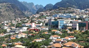 A densely packed hillside town with buildings, some with red-tiled roofs, and a prominent white arrow pointing downwards.